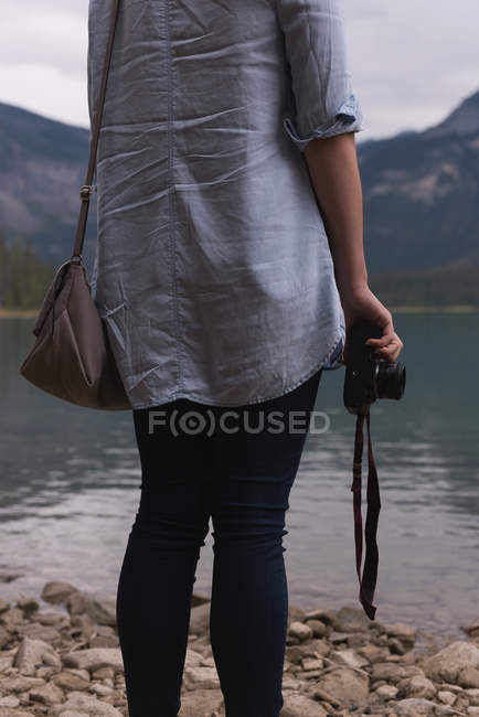 Frau strandet mit Kamera in Seenähe — Stockfoto