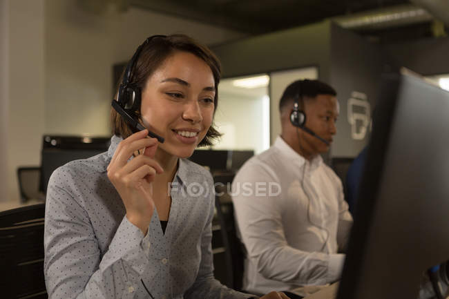 Ejecutivos de servicio al cliente hablando en auriculares en el escritorio en la oficina - foto de stock