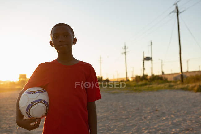 Ritratto di ragazzo che tiene il calcio nel terreno — Foto stock