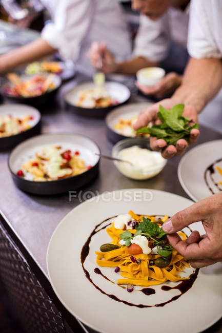 Nahaufnahme des Küchenchefs beim Garnieren von Speisen auf Tellern — Stockfoto