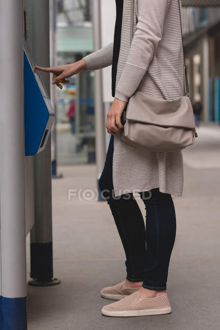Низкая часть женщин пользуется автоматом по продаже билетов на вокзале — стоковое фото