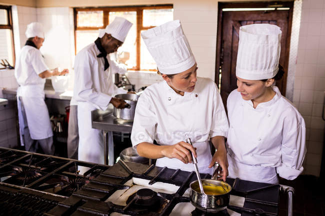 Köchin im Gespräch bei der Zubereitung von Essen in der Küche eines Restaurants — Stockfoto