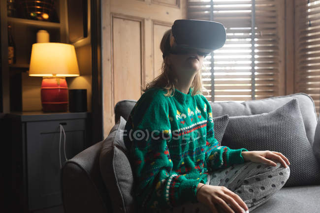 Жінка використовує гарнітуру віртуальної реальності на дивані вдома — стокове фото