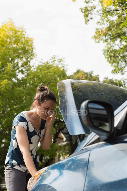Mulher falando no celular durante o colapso do carro em um dia ensolarado — Fotografia de Stock