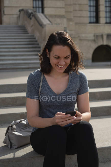 Жінка використовує мобільний телефон в місті в сонячний день — стокове фото