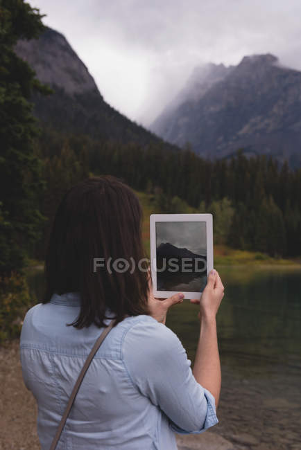 Rear view of woman clicking photos with digital tablet near lakeside — Stock Photo