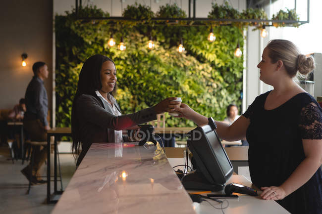 Офіціантка, що подає каву жінці-виконавцю на стійці в офісних кафетеріях — стокове фото