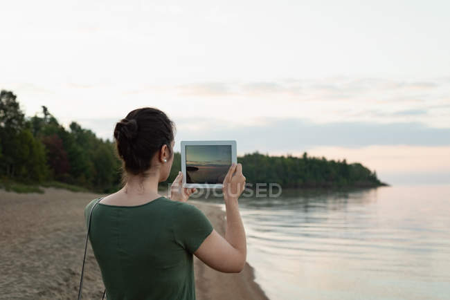 Vista trasera de la mujer haciendo clic fotos con la tableta digital - foto de stock