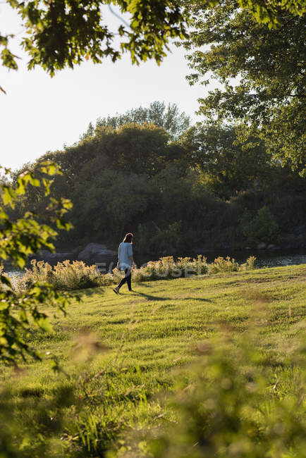 Mulher andando perto da ribeira em um dia ensolarado — Fotografia de Stock