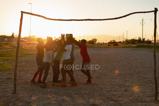 Дети играют в футбол в сумерках — стоковое фото