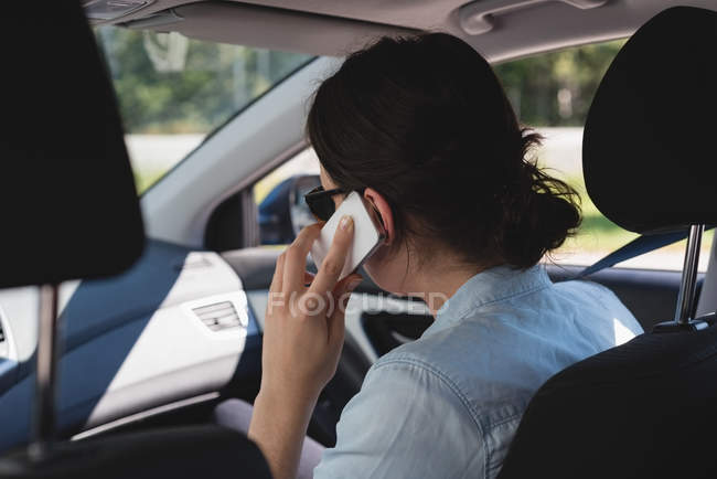 Vue arrière de la femme parlant sur son téléphone portable assis dans une voiture — Photo de stock