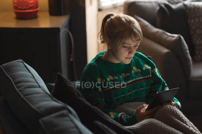 Woman using digital tablet on sofa in living room at home — Stock Photo