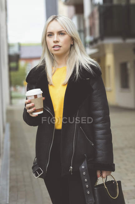 Stylish woman standing with coffee cup — Stock Photo
