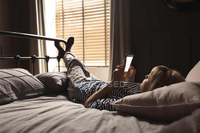 Жінка використовує мобільний телефон на ліжку в спальні вдома — стокове фото