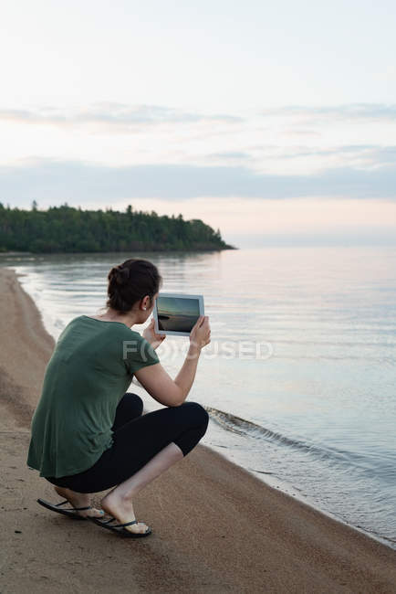 Vista trasera de la mujer haciendo clic fotos con la tableta digital - foto de stock