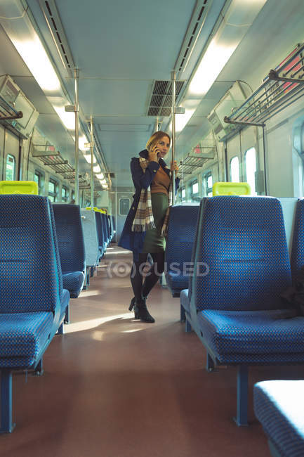 Hermosa mujer embarazada hablando en el móvil mientras viaja en tren - foto de stock