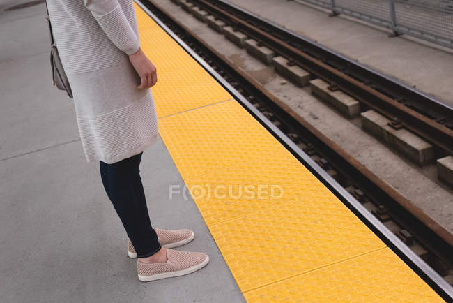 Нижняя часть женщины стоит на платформе на железнодорожном вокзале — стоковое фото