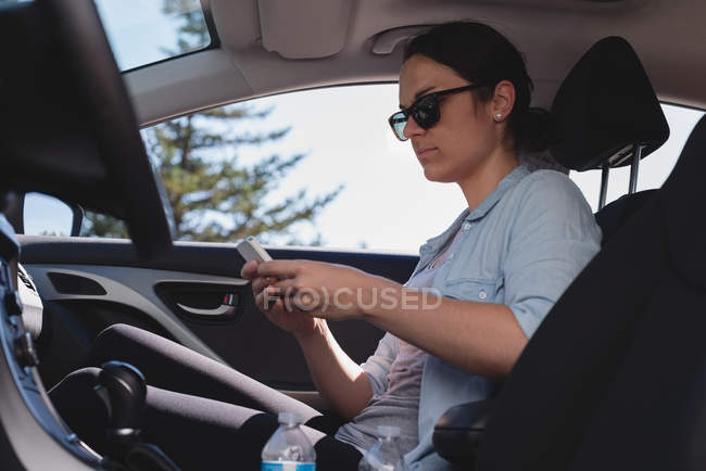 Belle femme utilisant mobile dans une voiture — Photo de stock