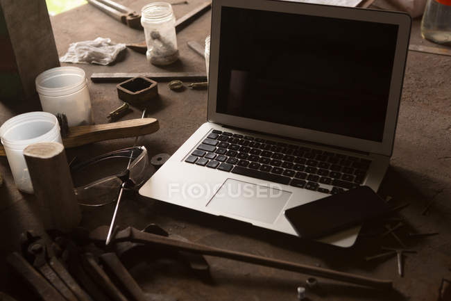 Close-up of laptop and mobile phone in metalsmith factory — Stock Photo