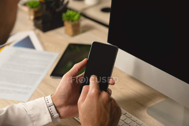 Керівник використовує мобільний телефон за столом в офісі — стокове фото