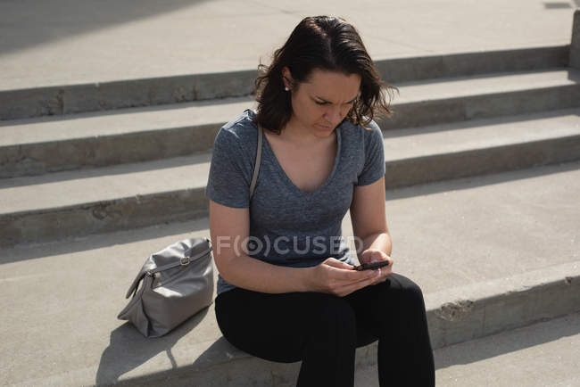 Женщина, использующая мобильный телефон в городе в солнечный день — стоковое фото