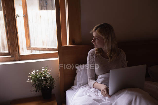 Mujer usando el ordenador portátil en el dormitorio en casa - foto de stock