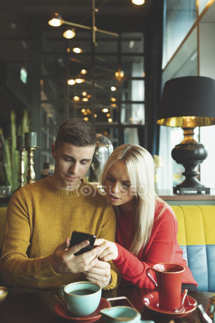 Пара обсуждений на мобильном телефоне в кафе — стоковое фото