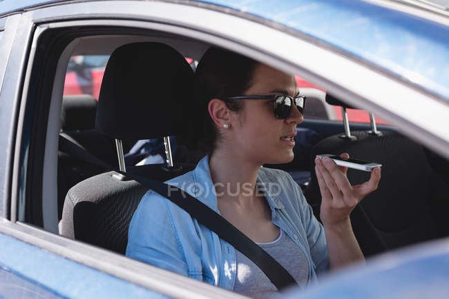 Красивая женщина разговаривает по мобильному телефону, сидя в машине — стоковое фото