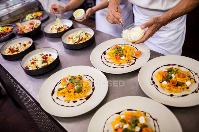Küchenchef garniert Speisen auf Tellern — Stockfoto
