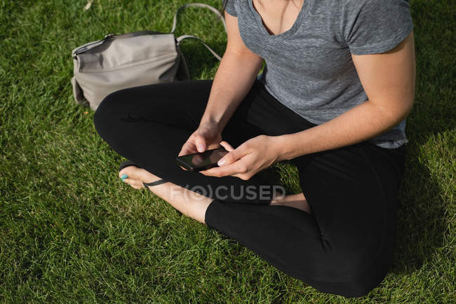 Frau benutzt Handy an einem sonnigen Tag im Park — Stockfoto