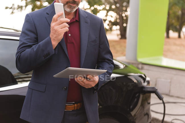 Mittelteil der Geschäftsmann mit digitalem Tablet während des Gesprächs auf dem Handy — Stockfoto