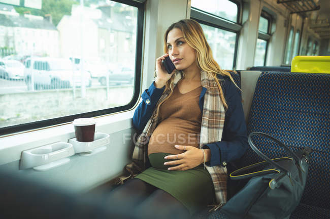 Mulher grávida bonita falando no celular enquanto viaja no trem — Fotografia de Stock