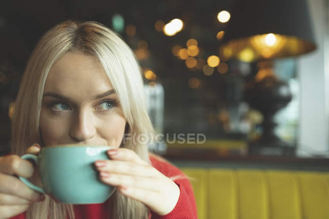 Primer plano de la mujer bebiendo café en la cafetería - foto de stock