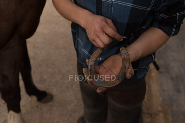 Partie médiane de la femme tenant un fer à cheval à l'écurie — Photo de stock