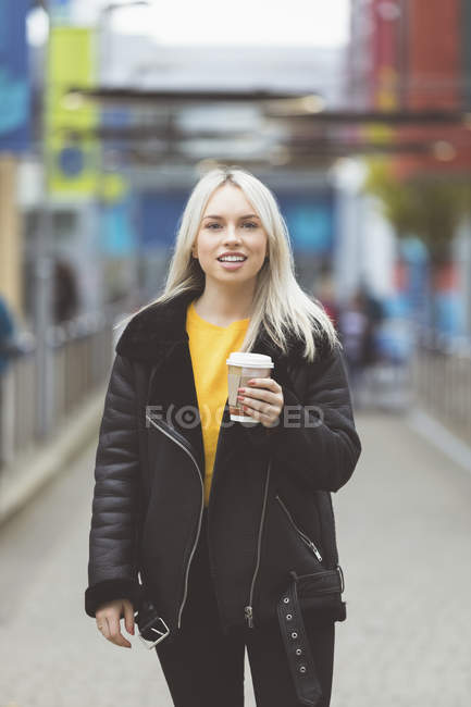 Lächelnde Frau, die beim Kaffee in die Kamera schaut — Stockfoto