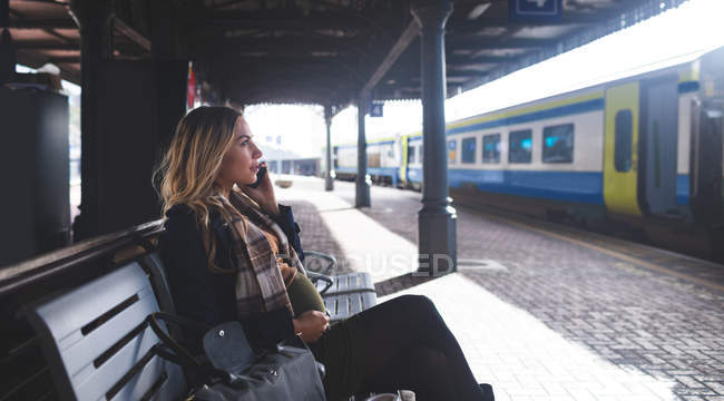 Vista lateral da mulher grávida falando no telefone celular na estação ferroviária — Fotografia de Stock