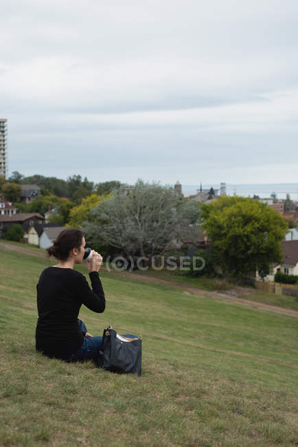Vue arrière de la femme prenant un café assis sur une colline — Photo de stock