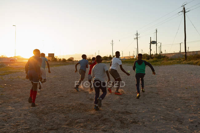 Enfants jouant au football dans le sol au crépuscule — Photo de stock