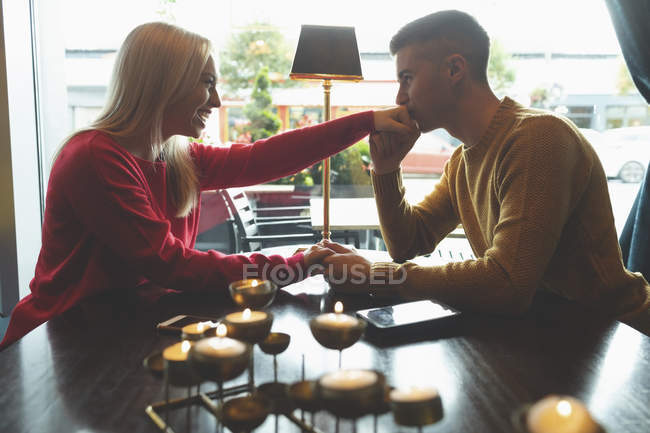Junger Mann küsst Frau in Café die Hand — Stockfoto