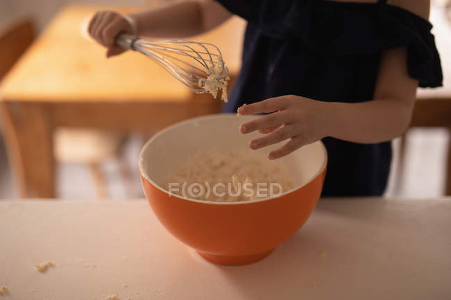 Sección media de la niña preparando comida en la cocina en casa - foto de stock