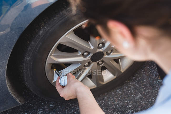 Close-up de mulher verificando um pneu em uma estrada — Fotografia de Stock