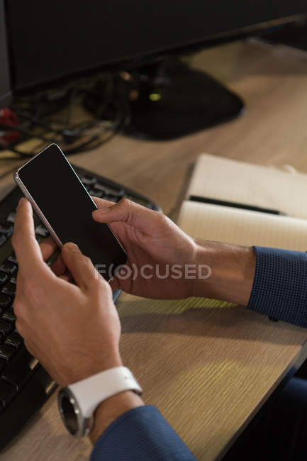 Close-up of executive using mobile phone in office — Stock Photo