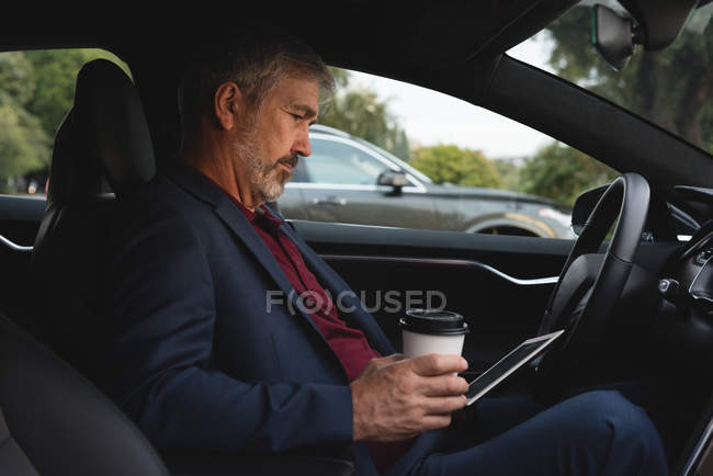 Side view of businessman using digital tablet in a car — Stock Photo