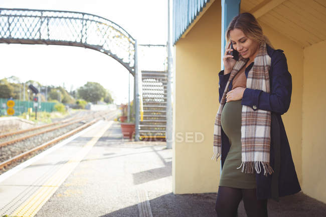 Schwangere telefoniert auf Bahnsteig am Bahnhof — Stockfoto
