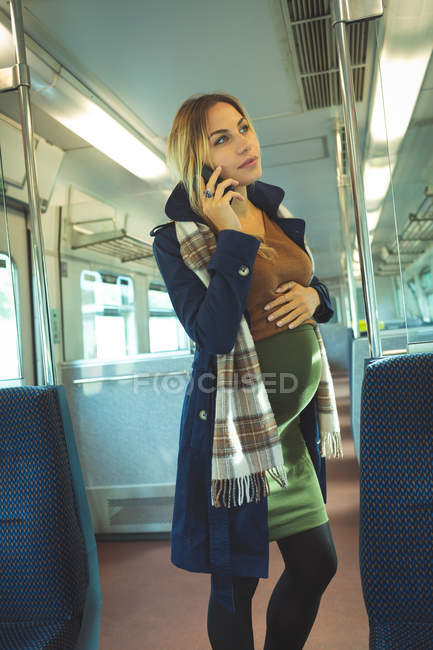 Schöne schwangere Frau, die während der Zugfahrt mit dem Handy spricht — Stockfoto