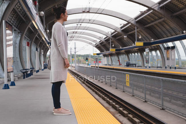 Thoughtful woman standing on platform at railway station — Stock Photo