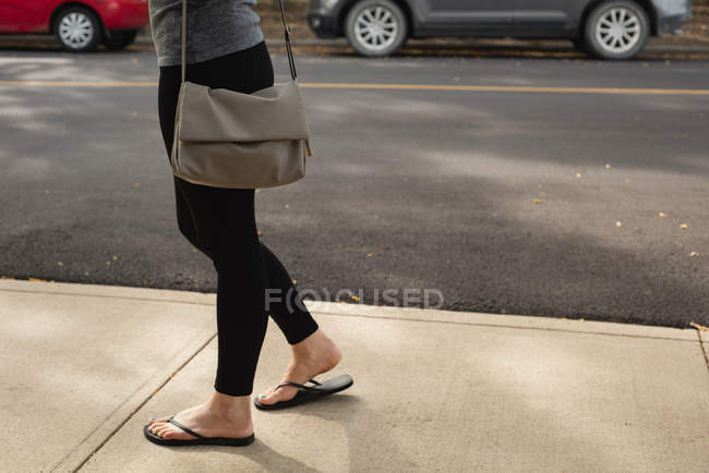 Sección baja de la mujer caminando en la calle - foto de stock