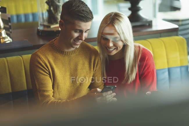 Пара смотрит на мобильный телефон в кафе — стоковое фото