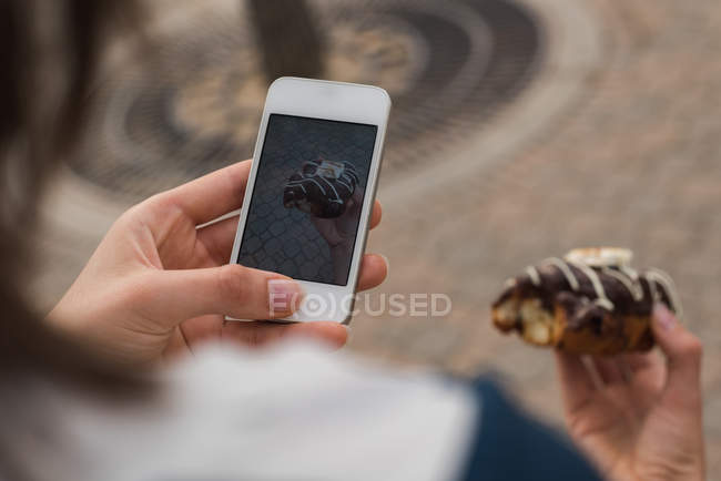 Close-up of woman clicking photo of doughnut — Stock Photo