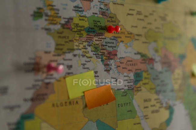Close-up of sticky notes and board pin attached on world map — Stock Photo
